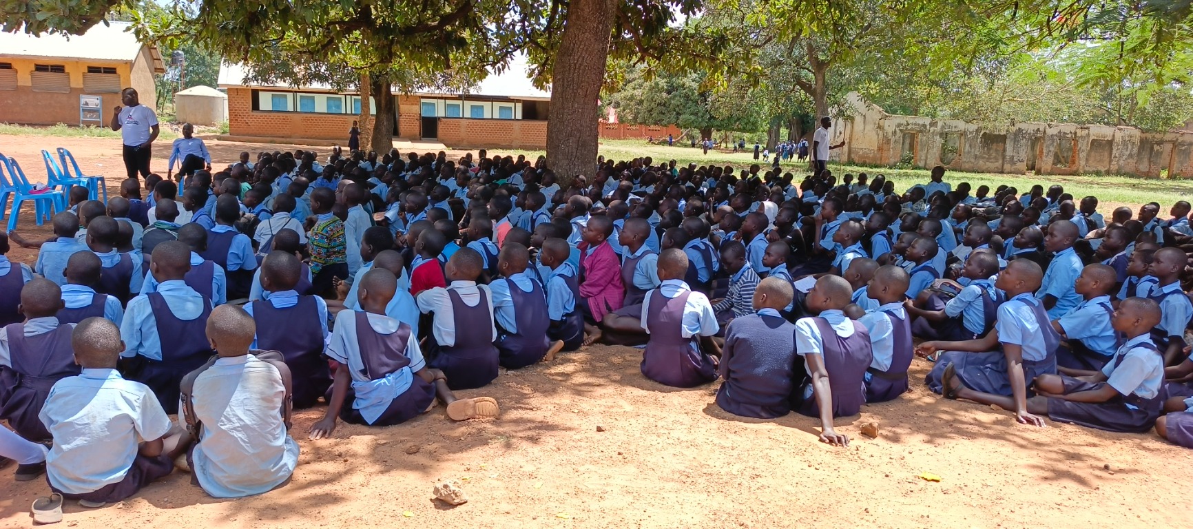 Students gathered beneath a tree for a community learning session