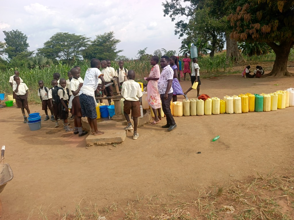 Students and community members gather at a school water point