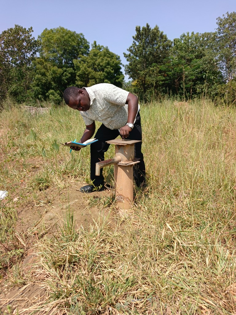 A field worker checks a hand pump during a site visit